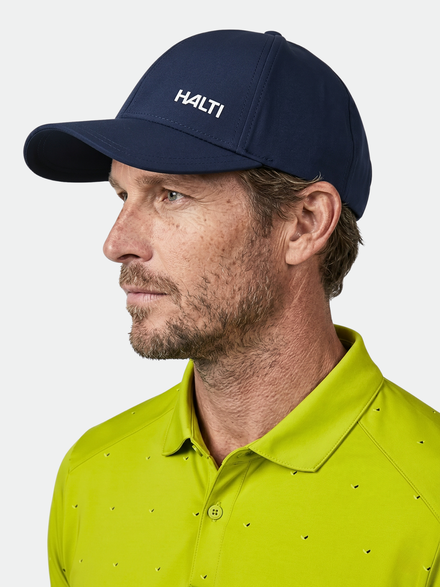 A man in a yellow-green shirt and Mattas Baseball Cap by Halti looks left; the cap offers UPF 50+ sun protection.