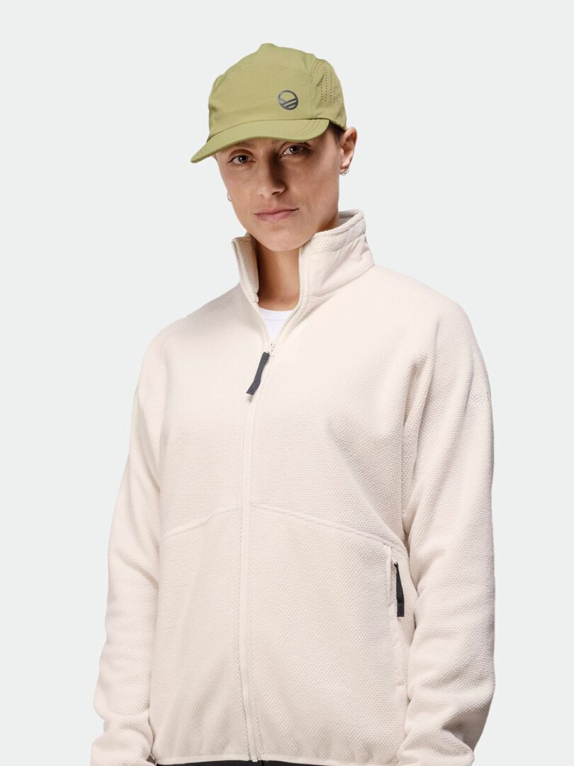 A person in a light beige zip-up jacket wears the Halti Aero II Cap, standing against a plain, light background.