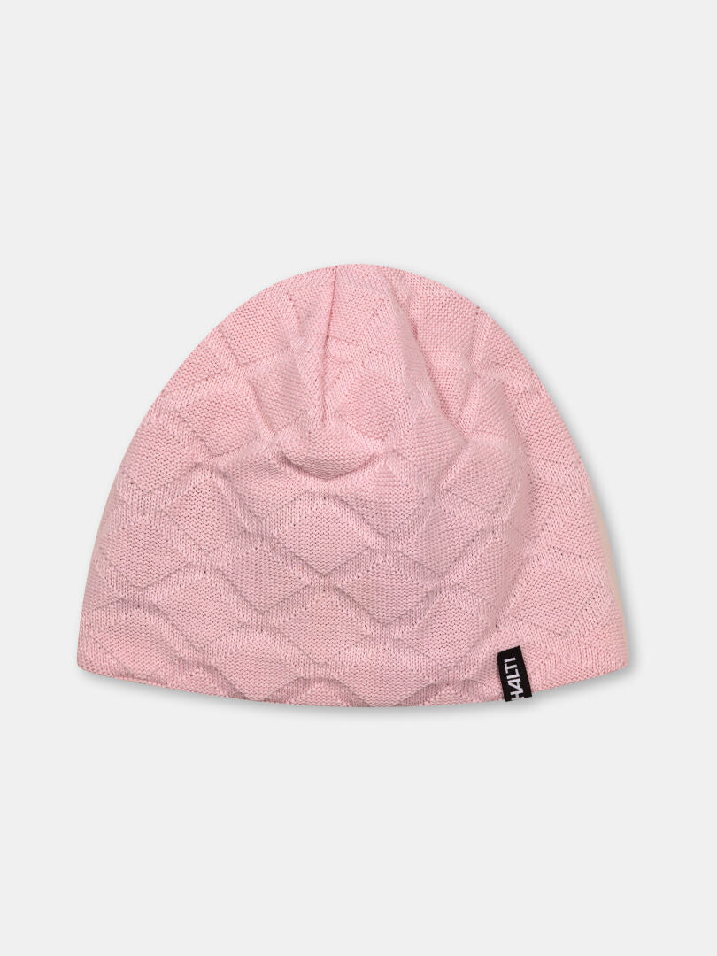 The Halti Crostie Merino Beanie is light pink with a diamond pattern and a small black tag, shown on a plain background.