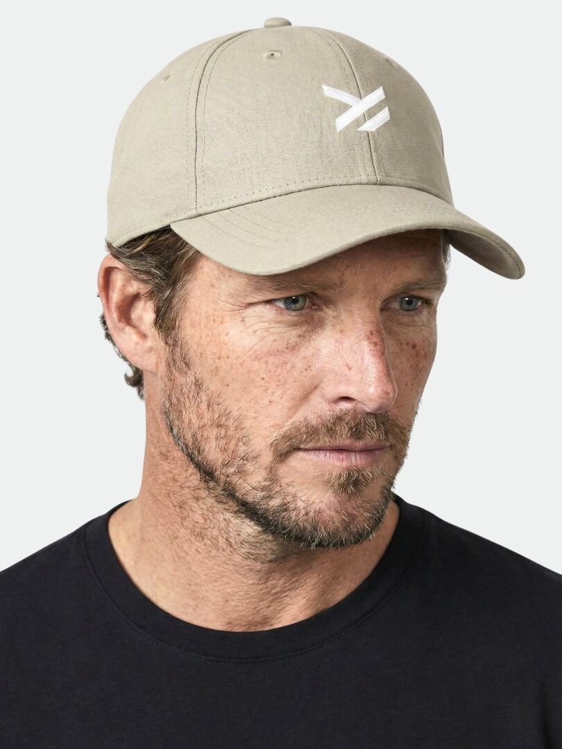 A man with a beard wears a beige Halti Notsgi Cap and a black shirt, looking slightly to the left.