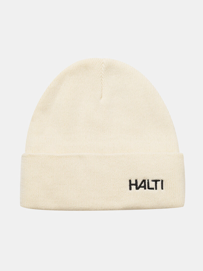 The Halti Justie Beanie is cream-colored, fleece lined, with a folded brim and black embroidered HALTI logo.