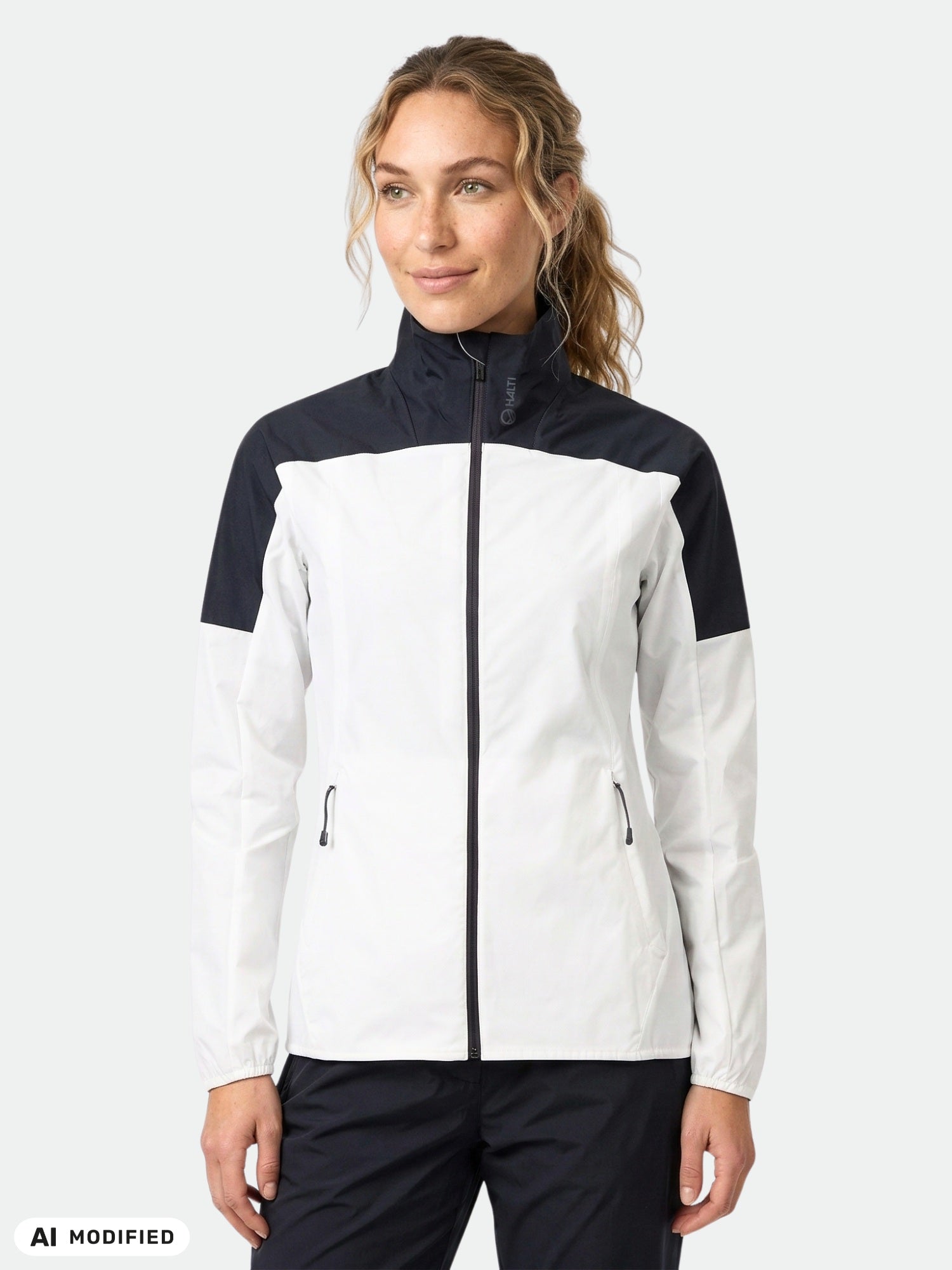 A woman wears the Halti Urbanite Training Jacket Women's with front pockets, standing against a plain background.
