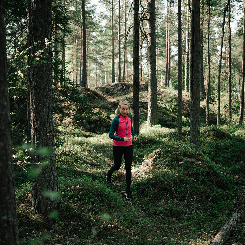 Wearing the Halti Tracks Womens Seamless Jacket, she jogs a sunlit forest trail, embracing active outdoor workouts.