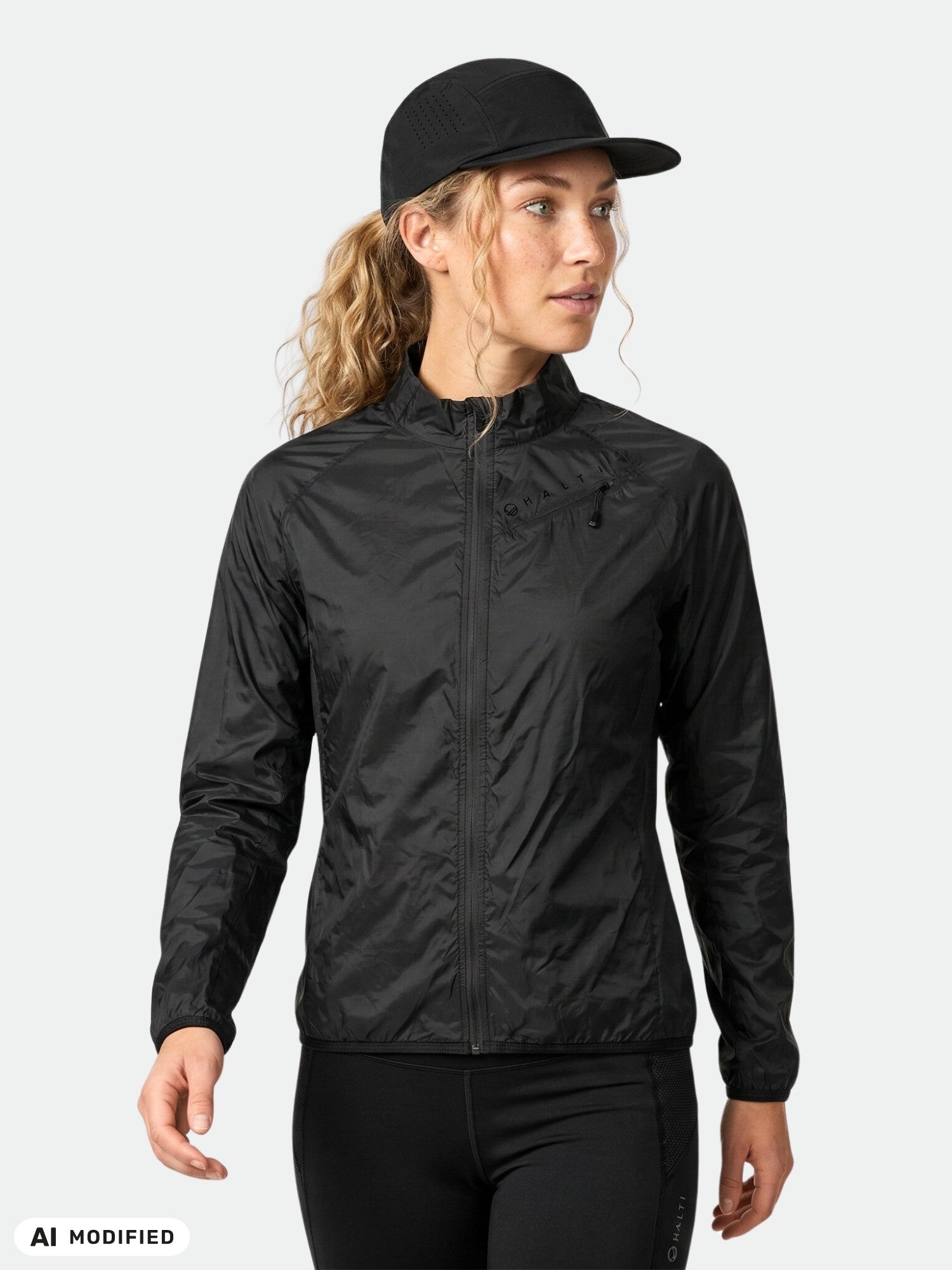 A woman wears the Halti Control Women's Windbreaker Jacket, cap, and pants against a plain light gray background.