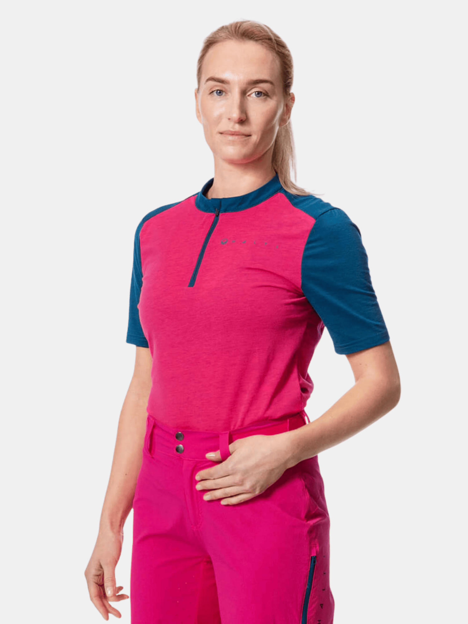 A person wears a pink and blue Halti Core Womens T-shirt with bright pink pants against a white background.