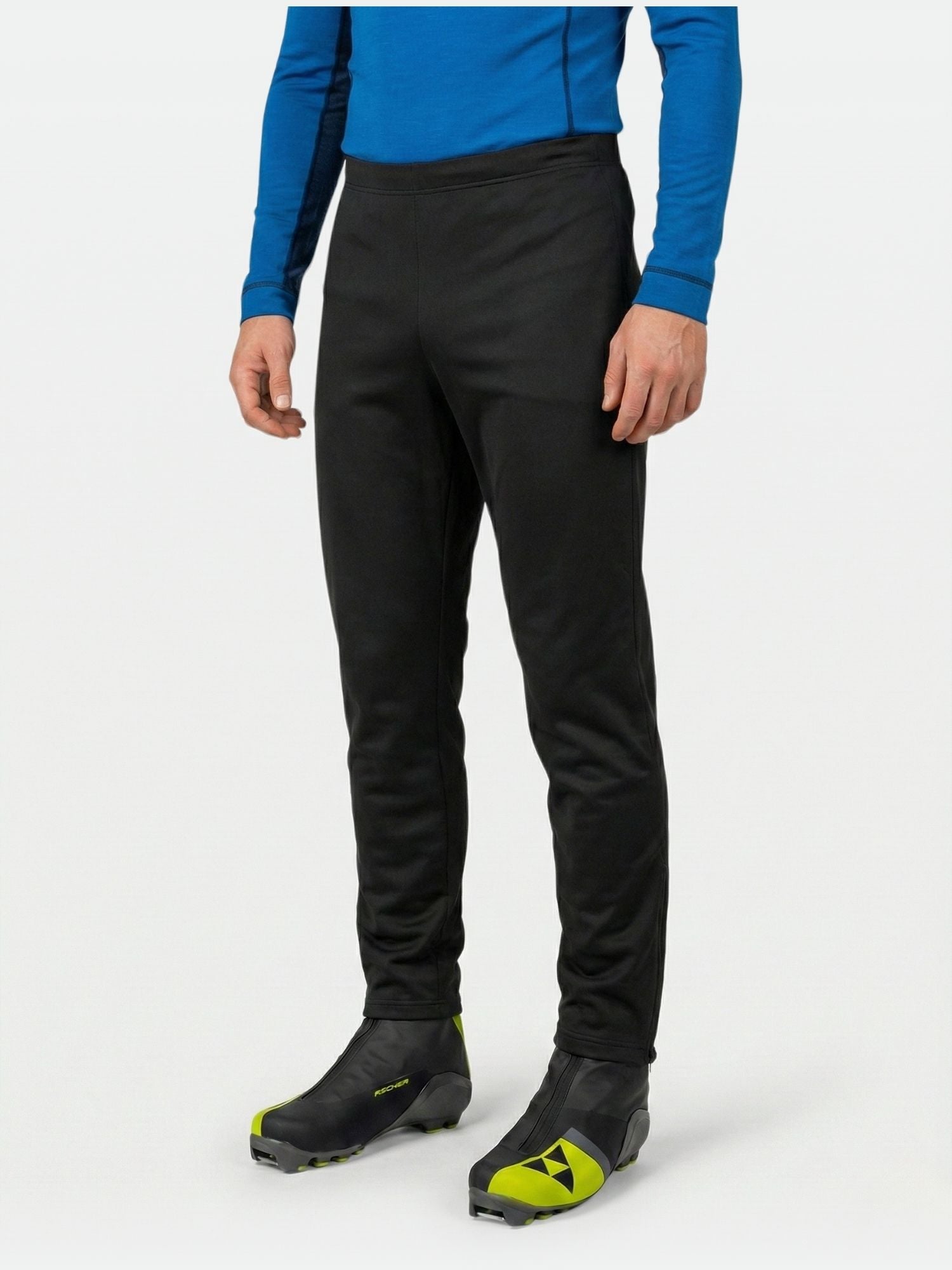 A person in Halti Isku II Men's XCT Pants, blue long-sleeve shirt, and black boots with yellow accents stands against white.
