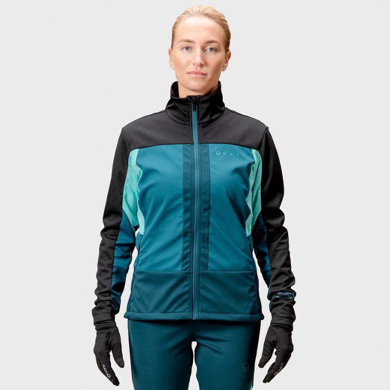 Person standing forward in Halti Vinha XCT Jacket Womens, teal pants, and black gloves against a plain background.