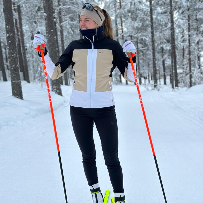 A woman in a Halti Vinha XCT Jacket is cross-country skiing on a snowy forest trail.