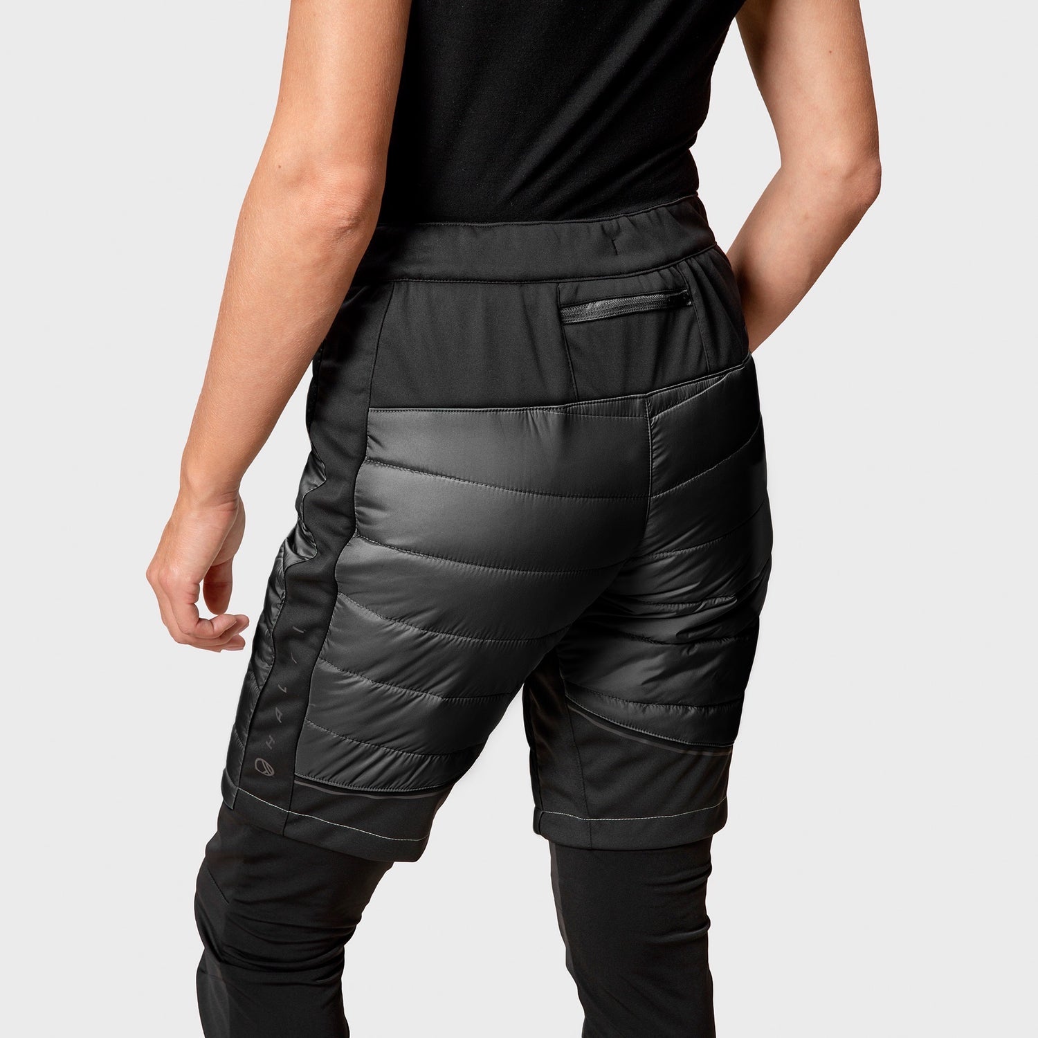 Woman wearing Halti Hanki Warm Hybrid Shorts with quilted detail, zip pocket, and windproof fabric.