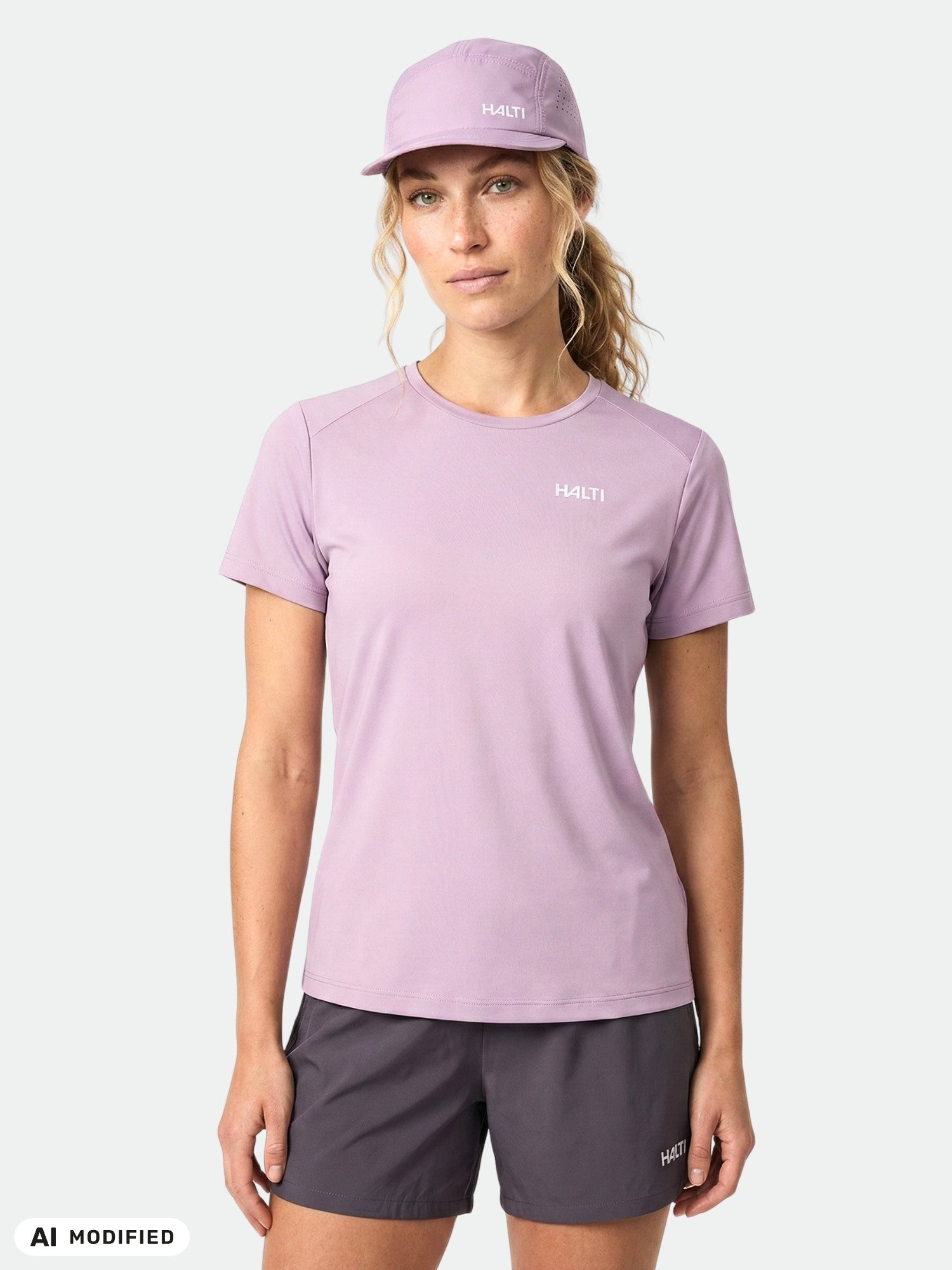 Woman wears Halti Salves T-shirt Women's, matching cap, and dark shorts against a white background.
