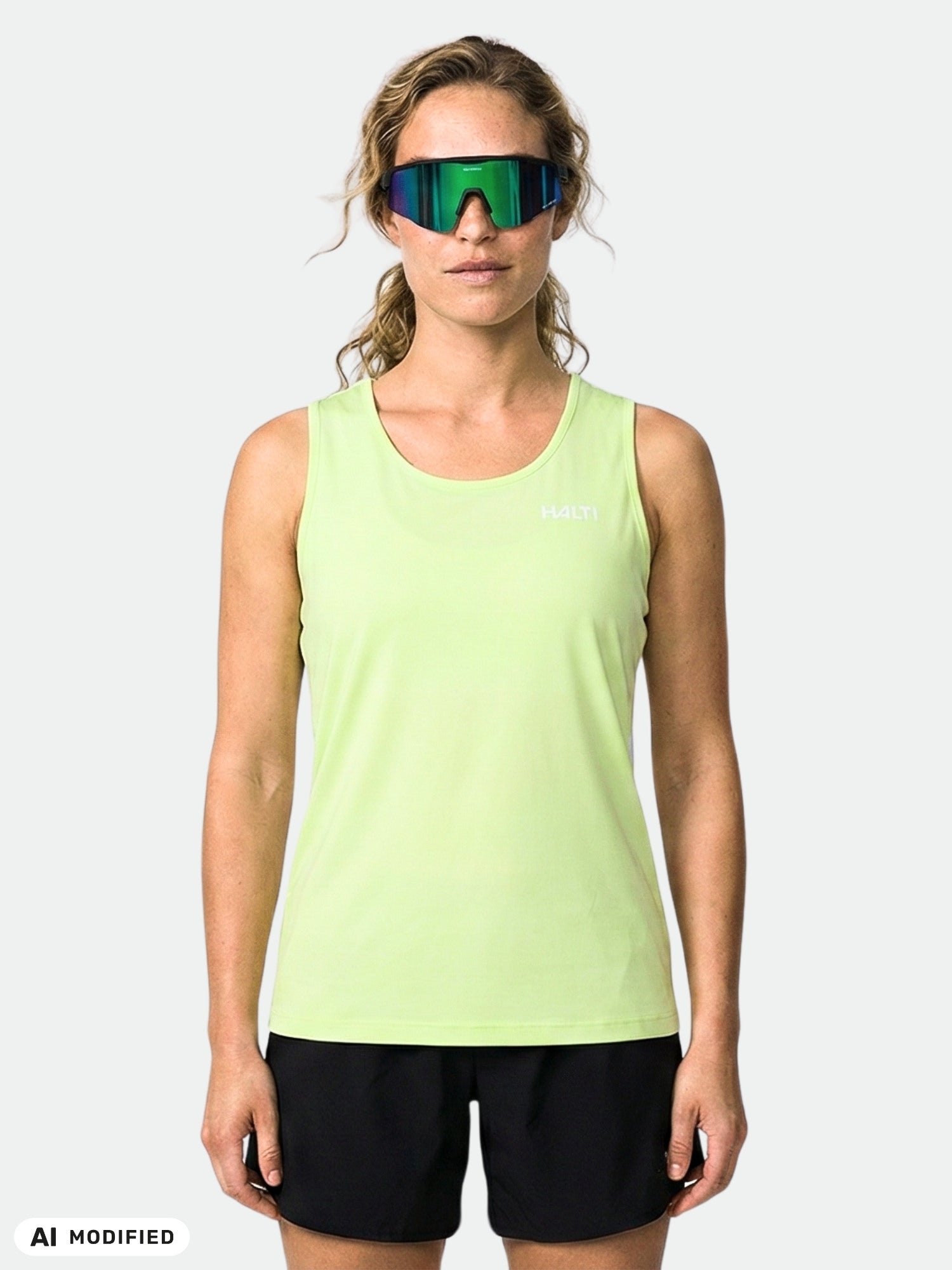 A woman faces forward in a Halti Salves Top Women's tank, paired with black shorts and sunglasses.