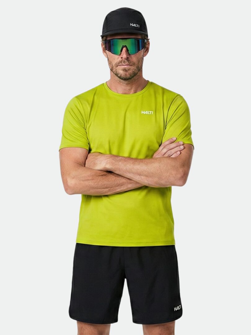 Man in a Halti Salves T-shirt—men's activewear made from recycled polyester, in lime green with black shorts and cap.