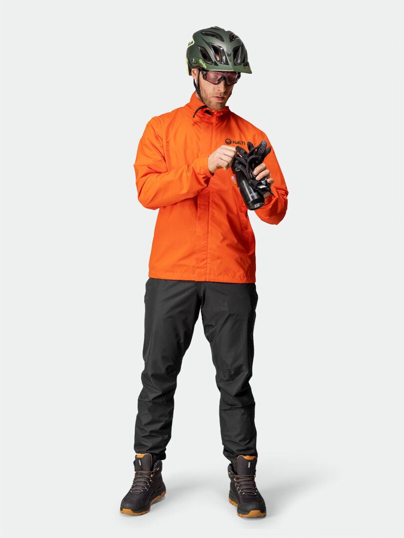 A person wears the Halti Triant DX Cycling Jacket Mens with reflective details, holding black gloves.