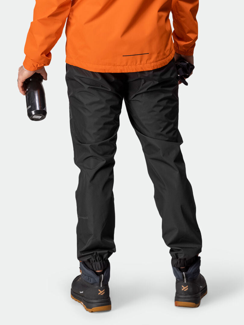 Person in orange jacket and Halti Triant DX mens cycling pants with reflectors, holding bottle, shown from behind.