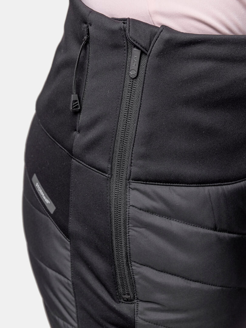 Close-up of Halti Hanki 2 Hybrid XCT Pants Women's, black weather-resistant with side zipper, over a light pink top.