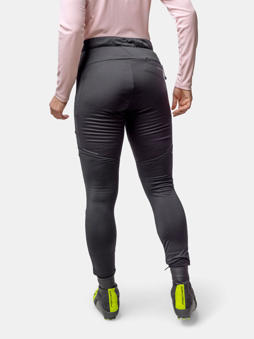 A woman in Halti Framover XCT Tights and neon green-black shoes, pink top, shown from the back.