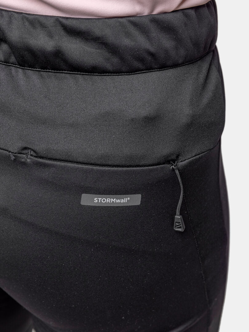 Close-up of a person wearing Halti Framover XCT Tights Women's with windproof fabric, zip pocket, and STORMwall logo on back.