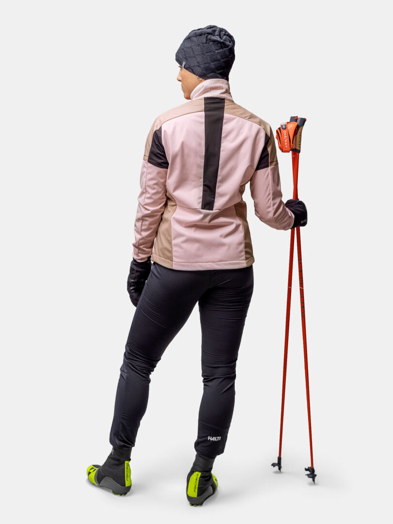 A woman in the Halti Huuru XC Set stands with ski poles, ready for winter training against a plain background.