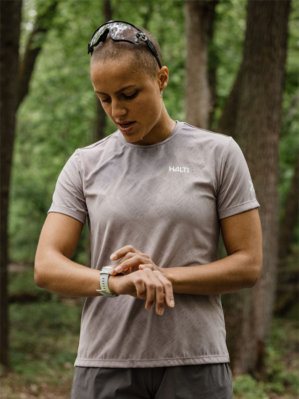Wearing the Halti Oulanka T-shirt Women's, a person in a forest checks their smartwatch.