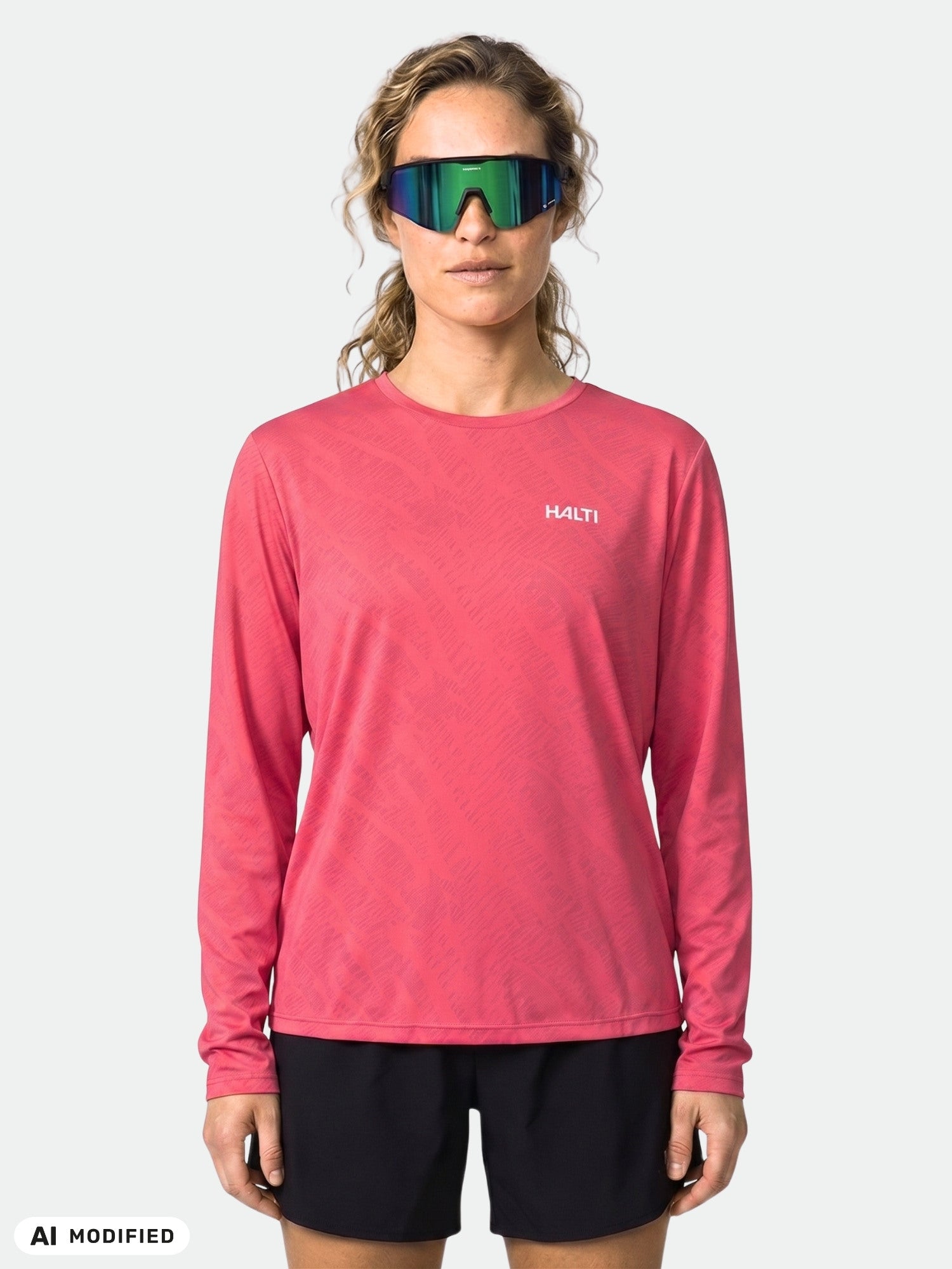 Woman in Halti Oulanka Training Shirt and black shorts with reflective sunglasses stands against a plain background.