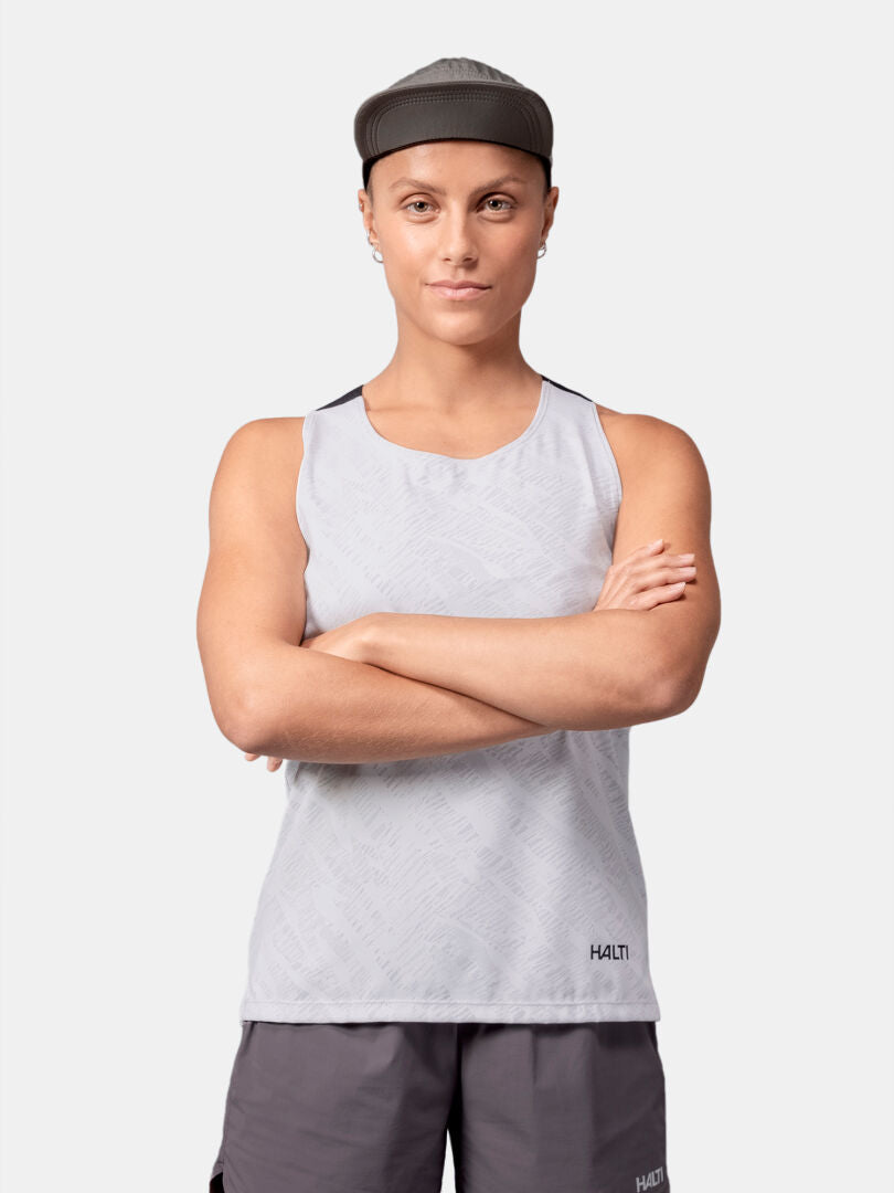 A woman wears the Halti Oulanka Training Top and gray shorts, standing with arms crossed against a plain background.