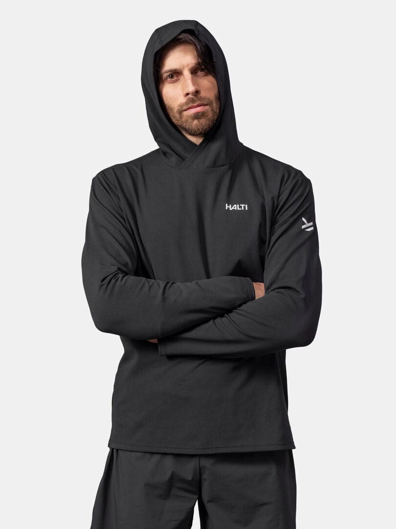 A man wears a black Halti Kaltio Training Hoodie, arms crossed, standing against a plain background.