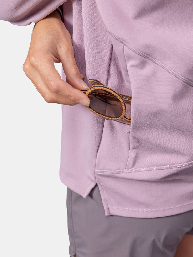 A person puts sunglasses in the pocket of a light purple Halti Kaltio Training Hoodie, paired with matching shorts.