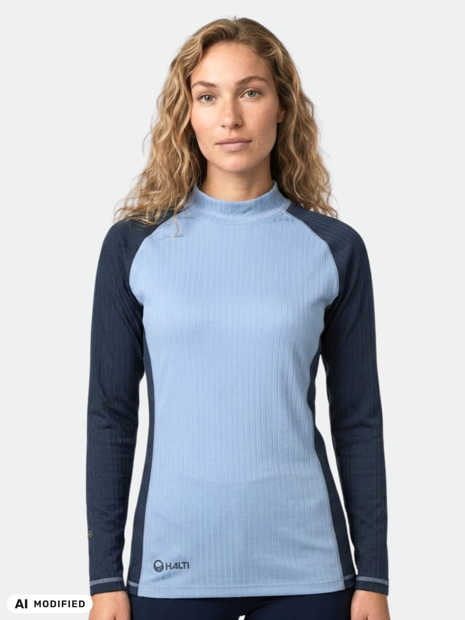 A person with long wavy hair wears the Halti Dual Base Layer Set Women's—a light blue top with dark sleeves.