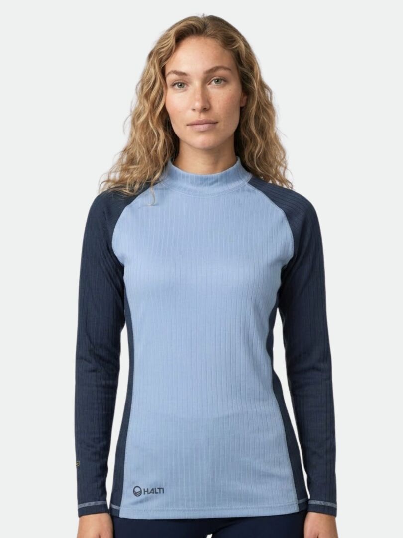 A person with long wavy hair wears the Halti Dual Base Layer Set Women's—a light blue top with dark sleeves.