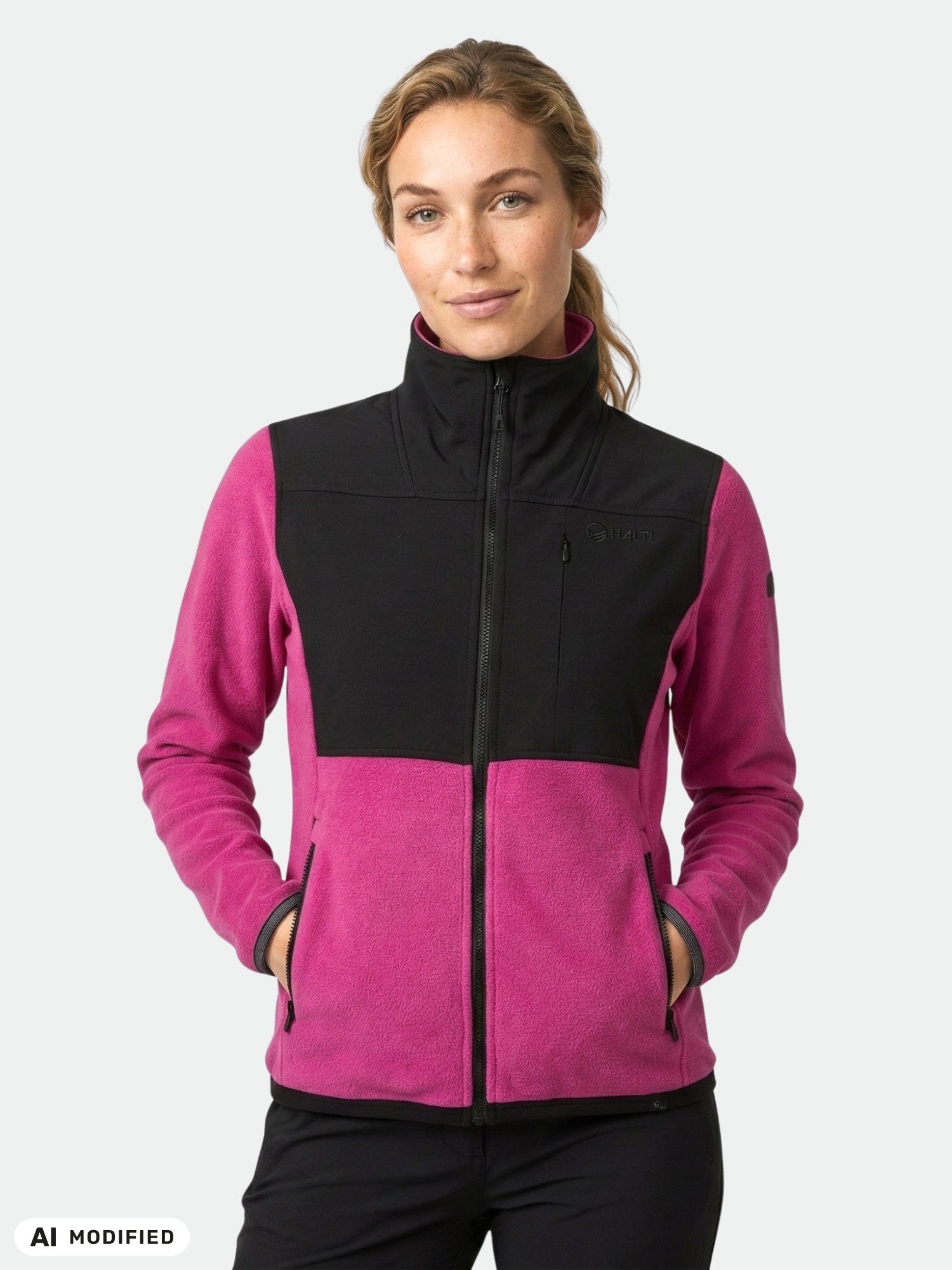 Woman in Halti Pioneering Fleece Jacket, magenta/black, stands hands-in-pockets—perfect mid layer for outdoors.
