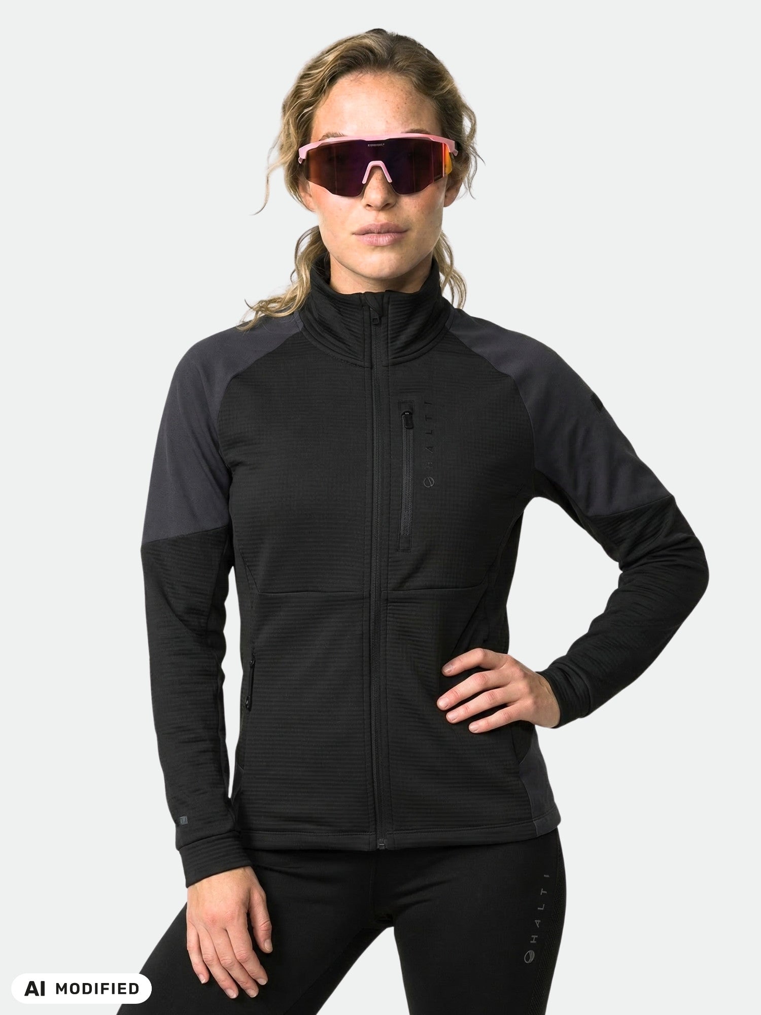 Woman in Halti Forerunner Layer Jacket and large sunglasses, hand on hip, poses against a plain background.