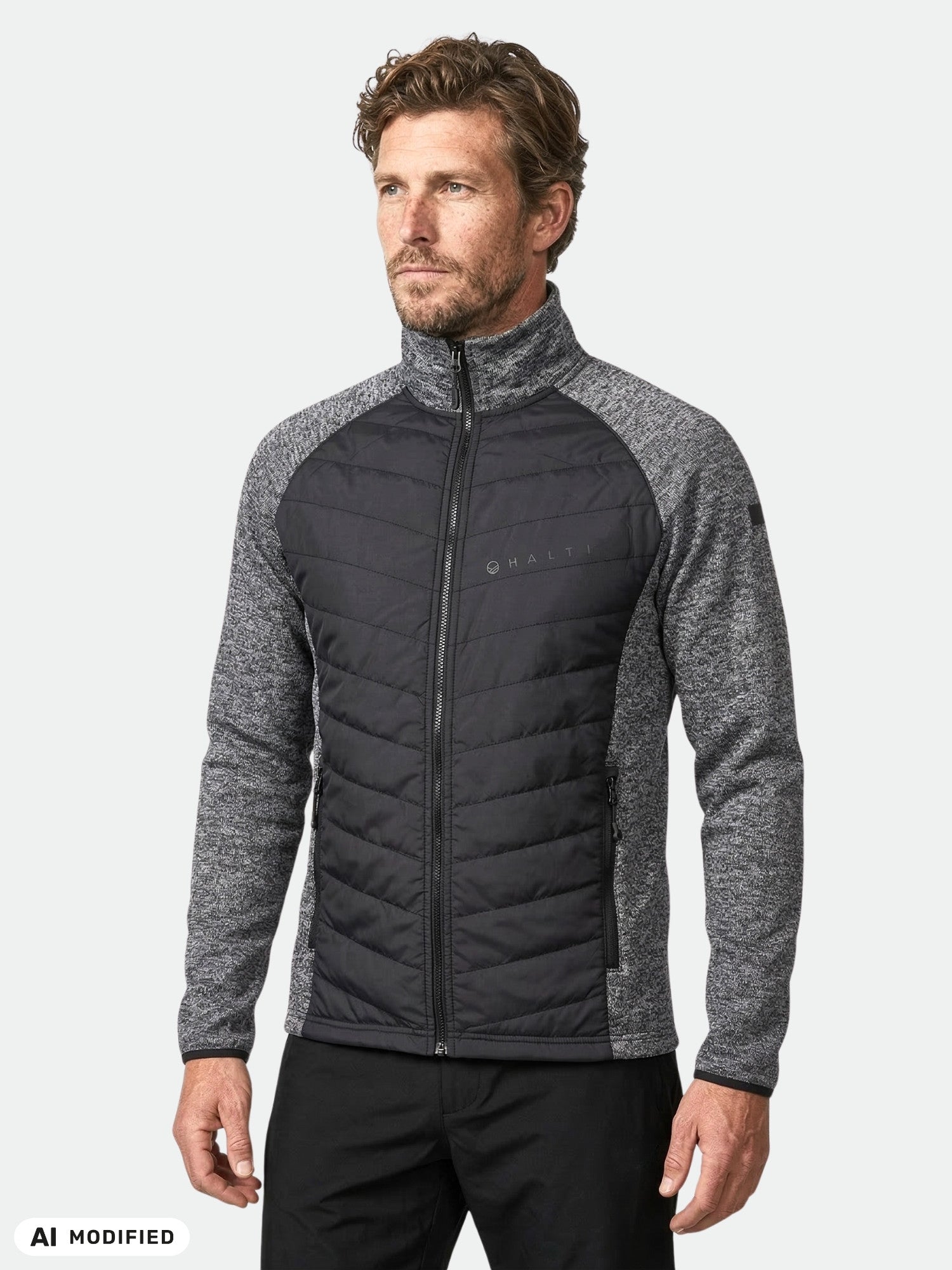 A man wears a Halti Streams Hybrid Layer Jacket Men's in gray and black with textured sleeves, on a plain white background.