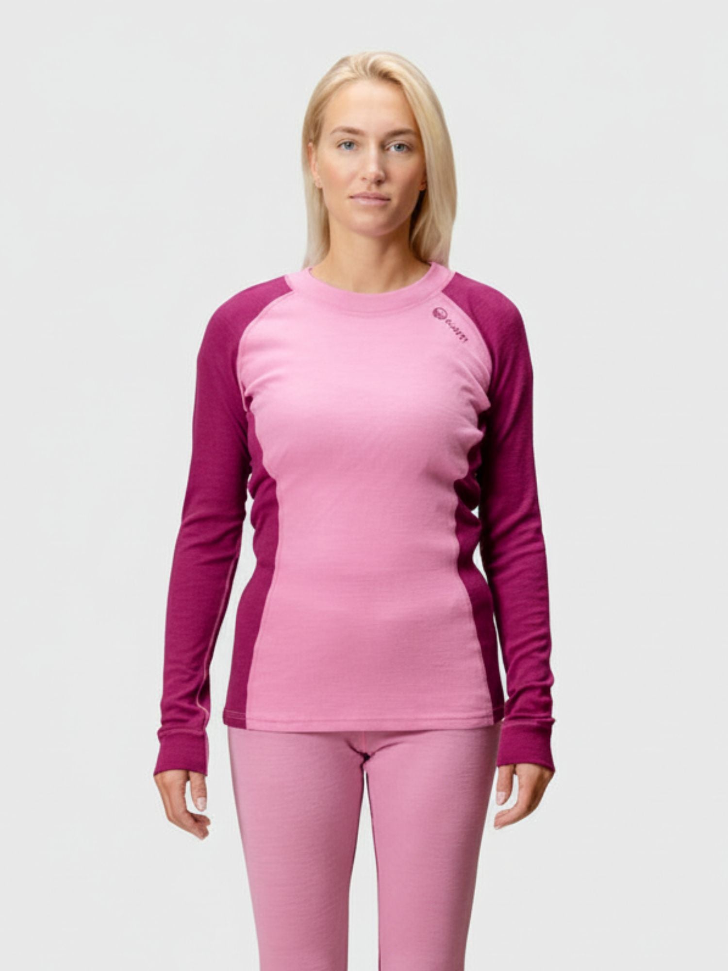 A woman faces forward, wearing the Halti Hossa Merinowool Baselayer Set Women's in pink with long-sleeve top and pants.