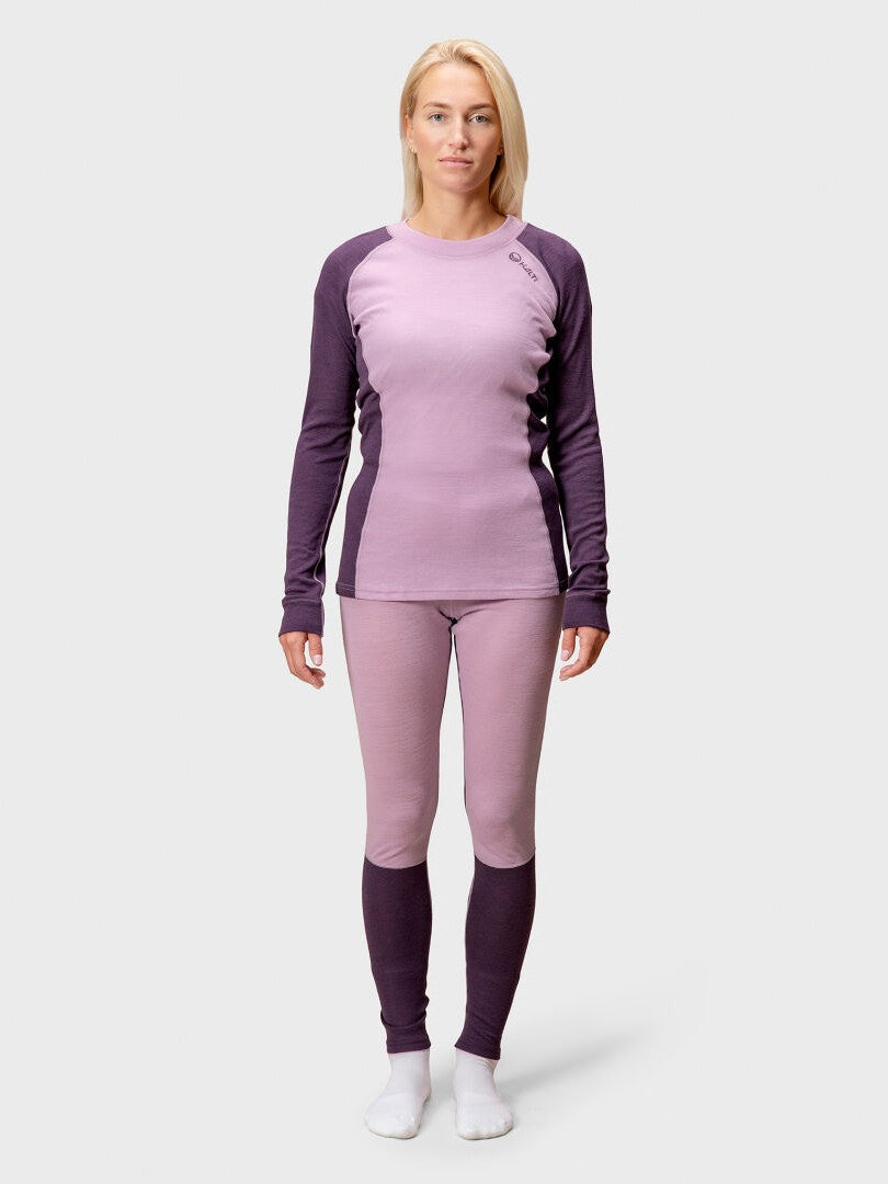 A woman wears the Halti Hossa Merinowool Baselayer Set Women's: two-tone purple top and matching leggings with white socks.