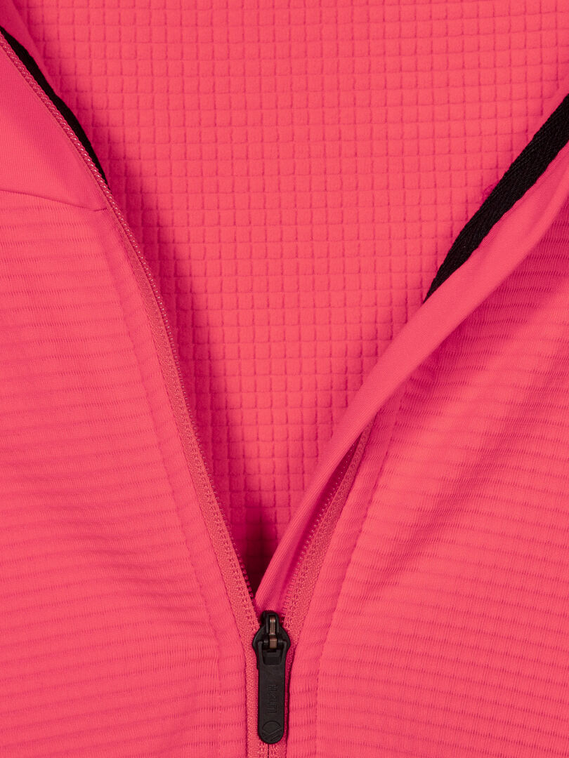 Close-up of Halti HeatGrid Layer Jacket Women's, partially unzipped with black zipper on a pink textured background.