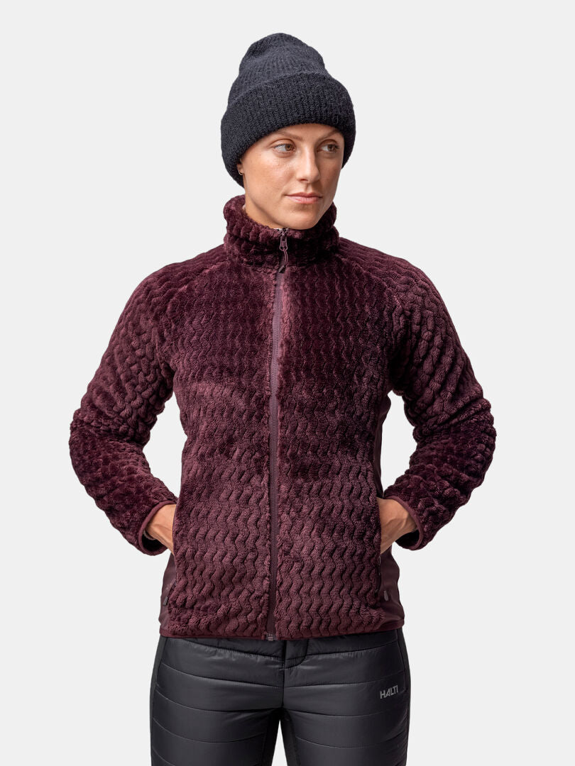 A person in a Halti Thermel Layer Jacket Womens, black knit beanie, and pants stands hands in jacket pockets.