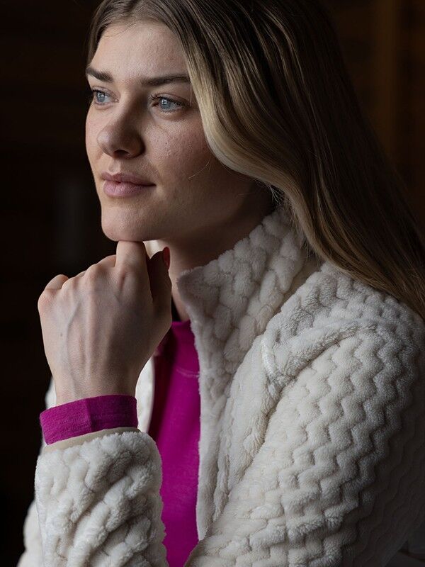 A woman in a Halti Thermel Layer Jacket Womens and pink shirt gazes thoughtfully into the distance.