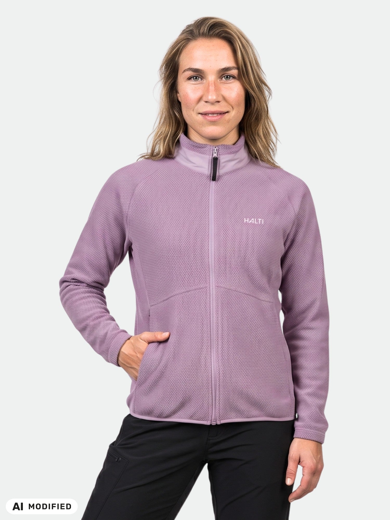 A woman wears the Halti Soolo Layer Jacket and black pants, posing against a plain background with one hand in her pocket.