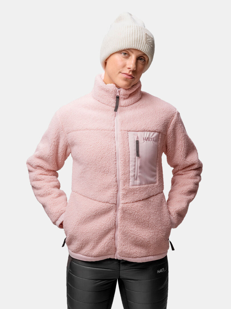 Model wears the Halti Lumista Polar Fleece Jacket in light pink with a white knit beanie and black pants against a plain backdrop.