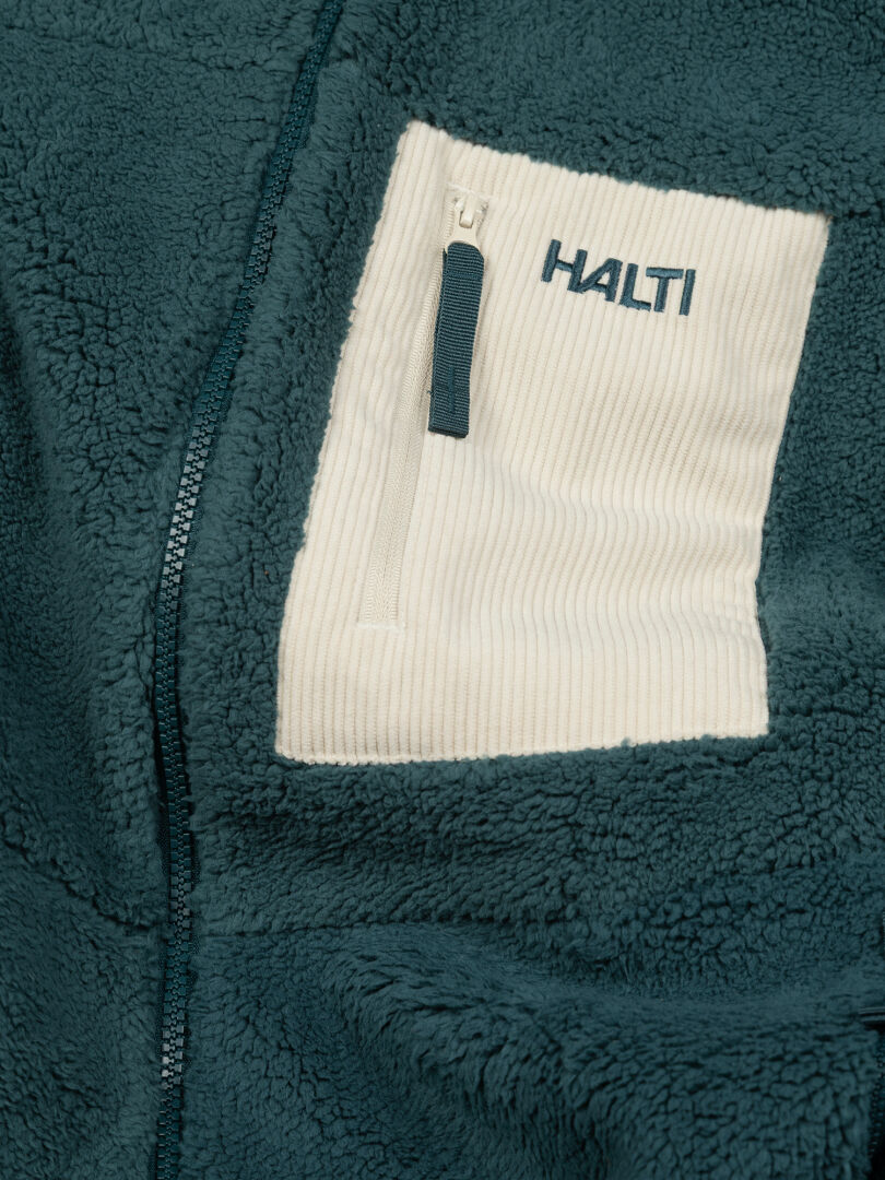 Detail of the Halti Lumista Polar Fleece Jacket Women’s in teal with a white chest pocket and logo above the zipper.