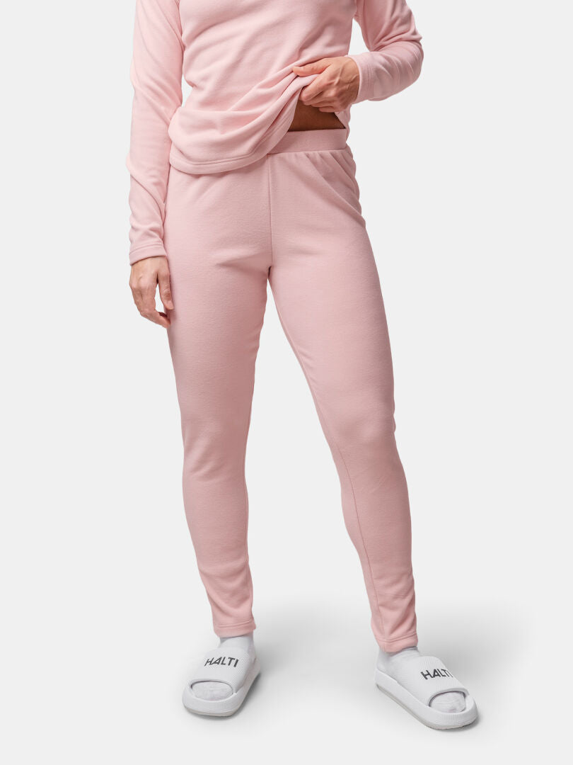 Person wearing light pink activewear top and Halti Trone Fleece Pants with white Halti slippers, against a plain background.