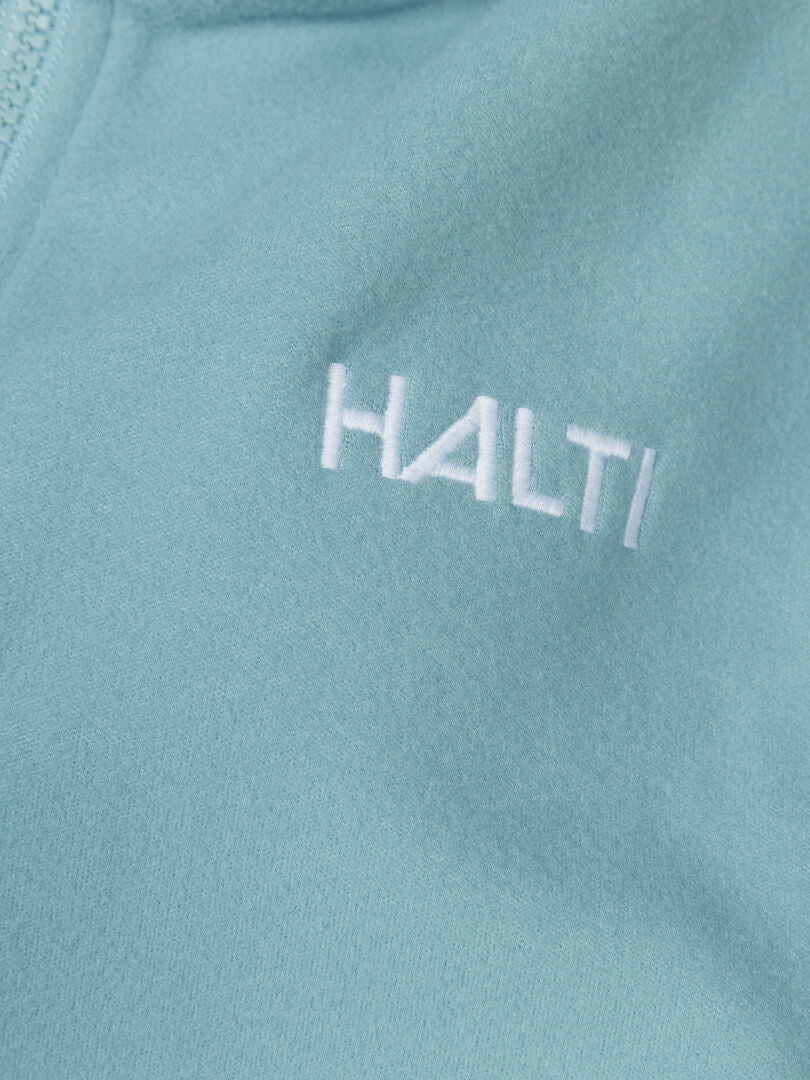 Close-up of Rockmoon Fleece Jacket Women's light blue stretch fabric with Halti logo embroidered in white.