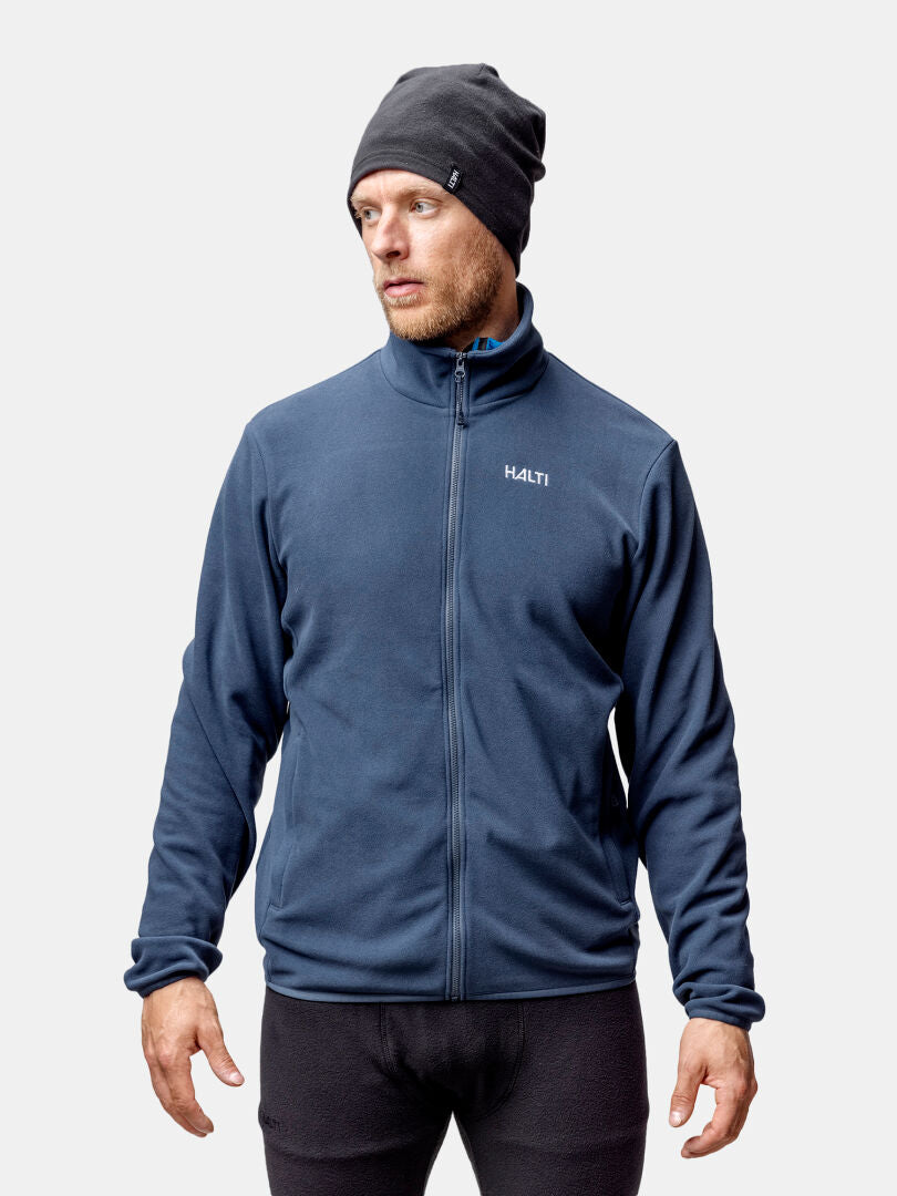 A man wears the Halti Rockmoon Fleece Jacket and a dark beanie, standing against a plain light background.