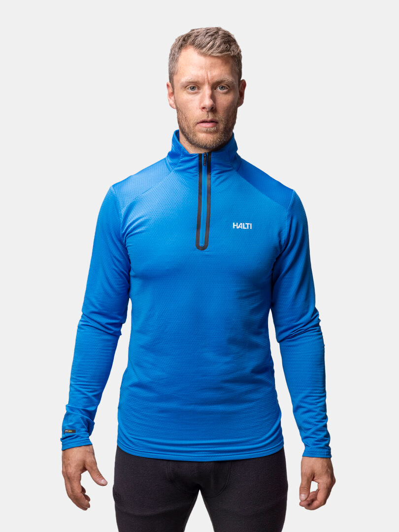 A man wears a bright blue Halti Jaako Shirt Men's, standing against a plain white background.