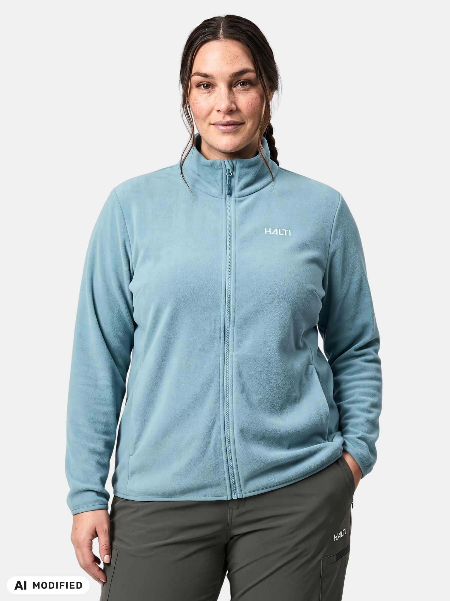 A person wears the Halti Rockmoon Fleece Jacket Women's Plus in light blue with dark pants, against a white background.
