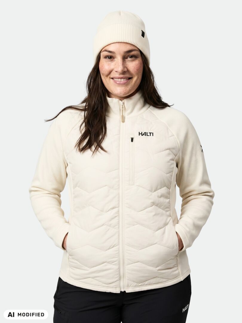 A woman wearing a cream-colored Halti Suomis Hybrid Layer Jacket Women’s Plus with quilted panels and a matching beanie.