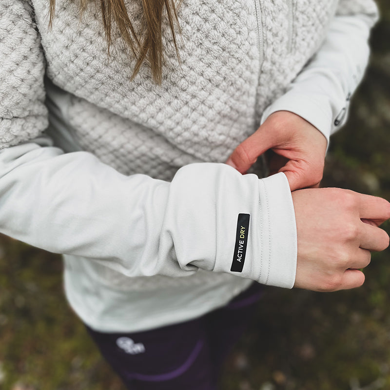 Woman wears Halti Forceful Womens Layer Jacket in light gray with ACTIVE DRY, made from recycled material, outdoors.