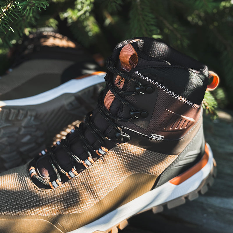 Close-up of Halti Kajava DrymaxX Womens waterproof outdoor shoes with orange details, on wood under pine branches.