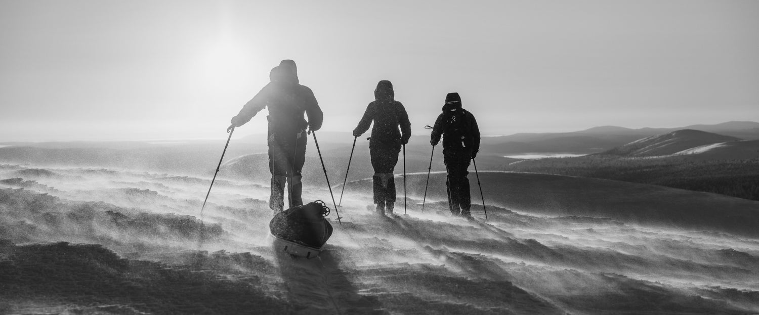 Three ski touring adventurers in snowstorm wearing Halti gear – black and white photo