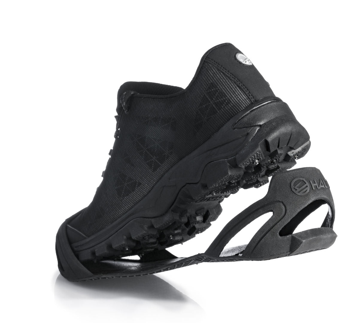 A black athletic shoe with the Halti Shoe Cover traction device and TR-rubber sole, angled to show the tread pattern.